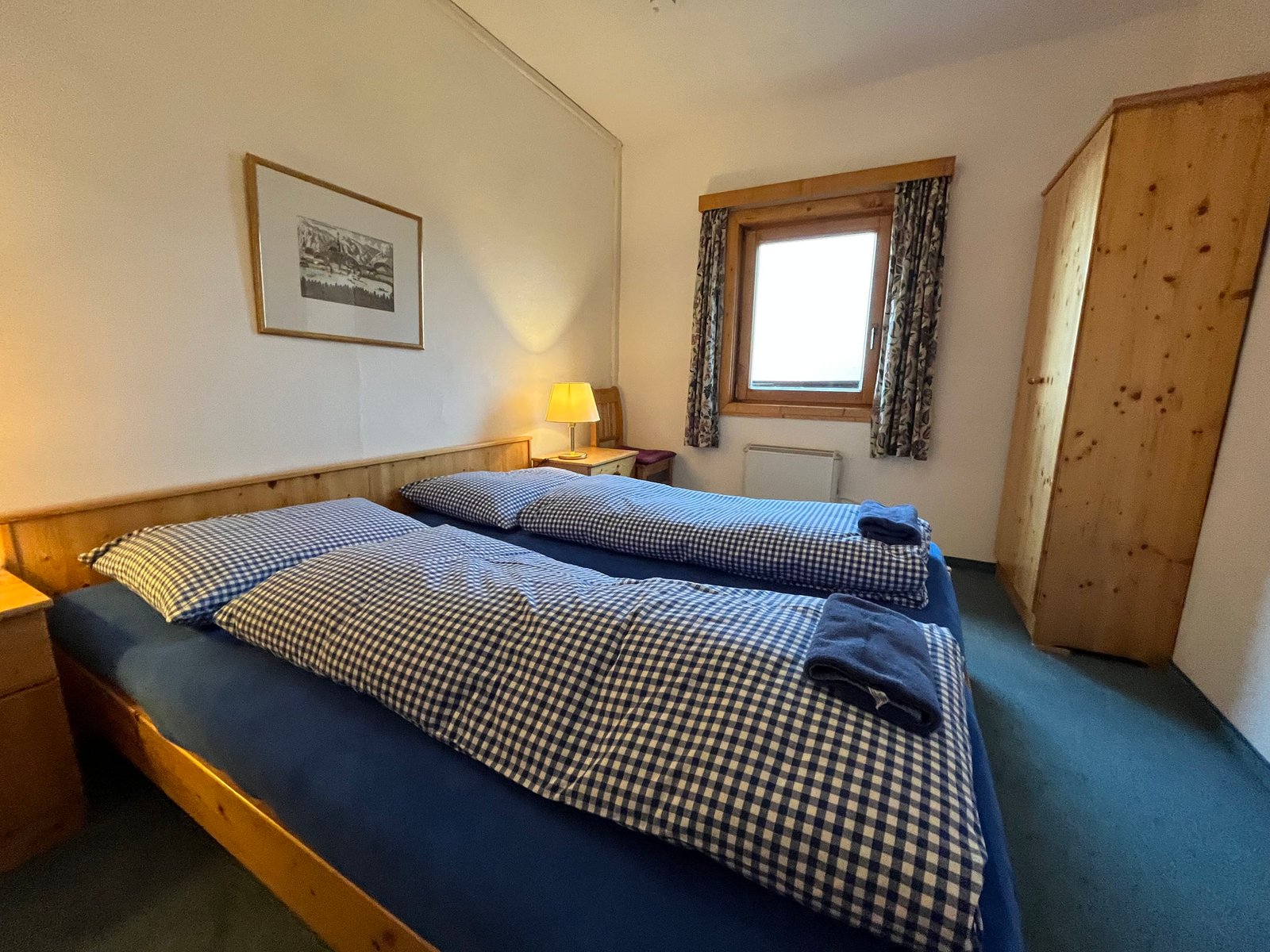 A simple twin room at Kranabethhütte with wooden furniture and blue checked bedding